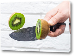   Постер Floating knife slicing trough kiwi fruit.